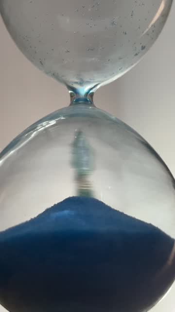 A hand holding an hourglass that represents time passing