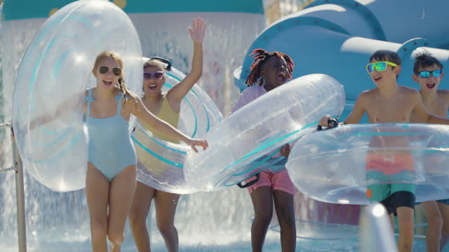 Children at water park run to lazy river with swim rings
