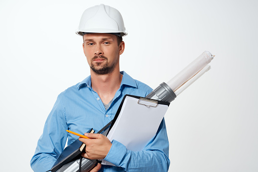 a man in a blue shirt in a construction helmet blueprints for construction professionals. High quality photo