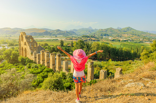 Tourist girl, enchanted by the ancient marvels of Turkey, explores the impressive Roman aqueduct of Aspendos. Against the backdrop of time-worn arches, she witnesses the ingenuity of Roman engineering