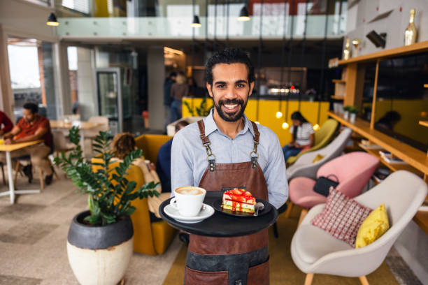 istock Confident Middle Eastern Male Bartender Smiling At The Camera While Holding A Drink Tray In A Charming Cafe 2051676448