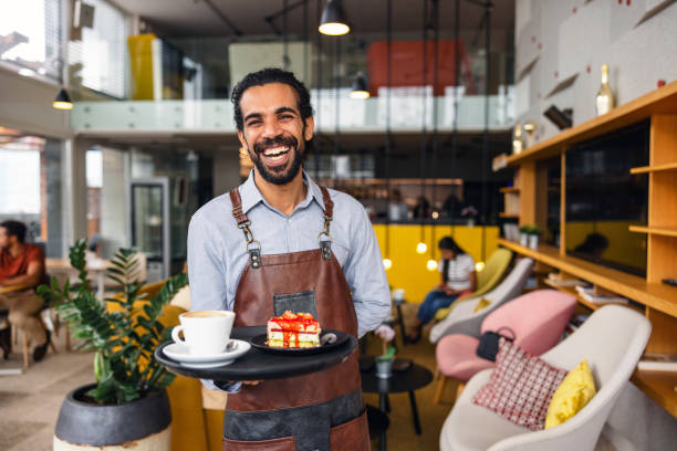 istock Happy Male Middle Eastern Bartender Laughing While Carrying A Tray With Drinks At A Bar 2051676449