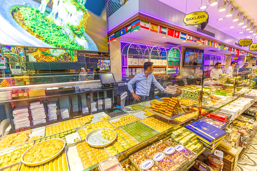 Istanbul, Turkey - Aug 2,2023: Colorful display of various baklava in a bustling turkish dessert store with staff serving customers. Traditional turkish baklava assortment at a sweet shop