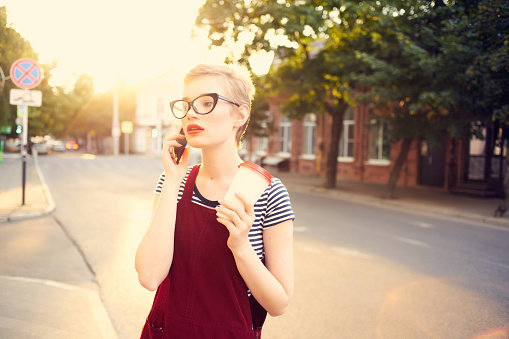 woman with short hair on the street talking on the phone a cup of drink. High quality photo