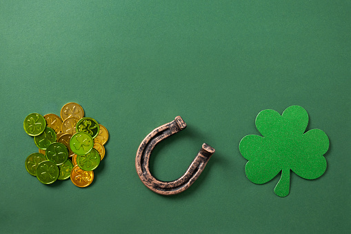 St. Patrick's day composition with clover leaf and horseshoe on green background. View from above. Copy space.