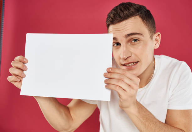 istock Puzzled young man on a red background are looking at a flyer in hand 2051823904