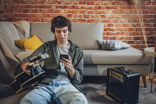 Male musician using smart phone in modern studio.