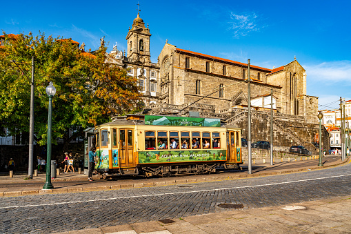Porto, Portugal - October 6, 2023: Tourists are riding the tram. The street view of Rua do Infante D. Henrique and Church of Saint Francis, Porto, Portugal.