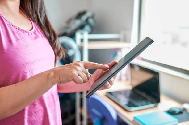 istock Close-up of woman pointing at online workout tutorial on digital tablet in home gym 2051844069