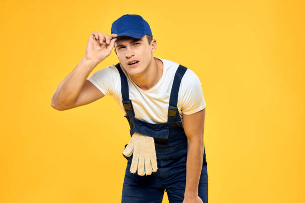 istock Working man in uniform of gloves rendering service yellow background 2051860203