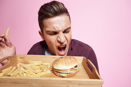 man in shirt french fries and hamburger pink background emotions. High quality photo