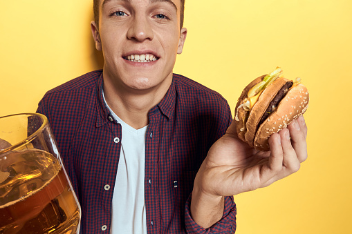 drunk man beer mug hamburger diet food yellow background. High quality photo