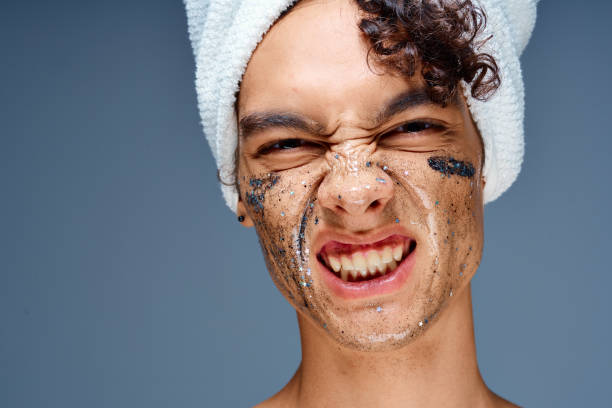 istock Cheerful guy with bare shoulders with a towel on his head, a black mask on his face 2051933664