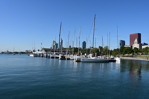 Chicago, Illinois - August 9, 2019: Chicago Yacht Club and city skyline reflected in calm Lake Michigan on cloudless summer morning.