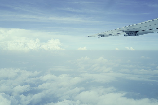 An airplane wing through airplane window with blue sky background