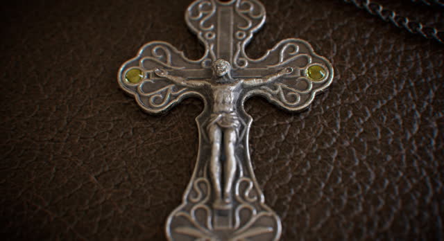 A metal crucifix fastened to a leather-bound religious manuscript.