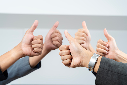 Thumbs up with hands of a business team or group giving their approval, saying thank you or giving motivation together in their office at work. Corporate professionals supporting with trust.