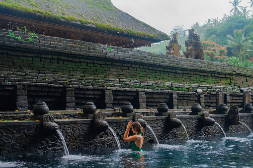 Woman doing purifying ritual in  Tirta Empul holy spring in Ubud, Bali, Indonesia