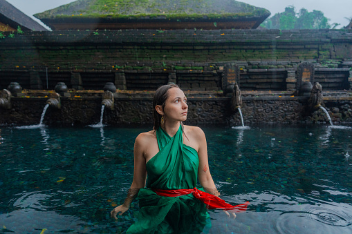 Woman doing purifying ritual in  Tirta Empul holy spring in Ubud, Bali, Indonesia