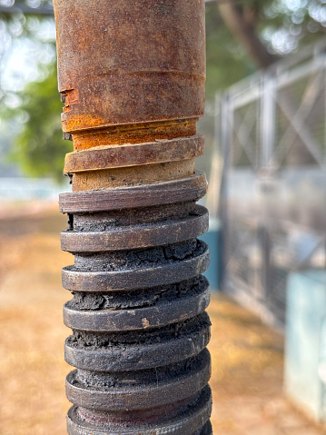 Close-up of a black metal spring on aged metal equipment, showcasing texture and decay.