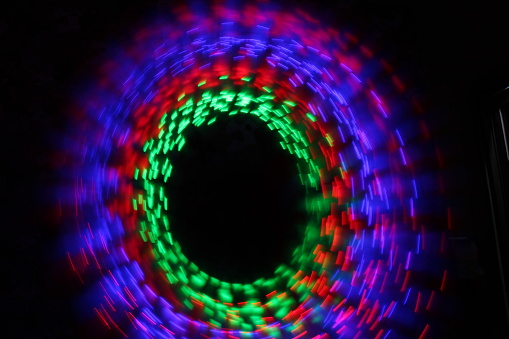 Blurred of Green, red and purple light painting photography, long exposure, ripples and waves against a black background