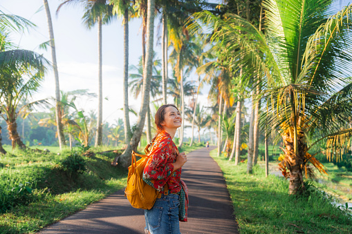 Cheerful woman  walking in coconut tree grove on Bali