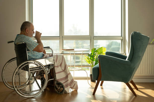 Patient in disabled chair mature man drinks water