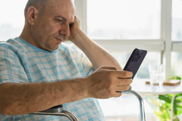 istock mature man in disabled chair looking at message on phone 2052208491