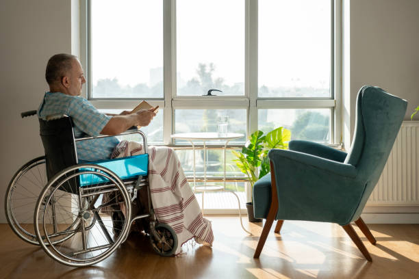 istock Mature man reading a book in a disabled chair 2052208494