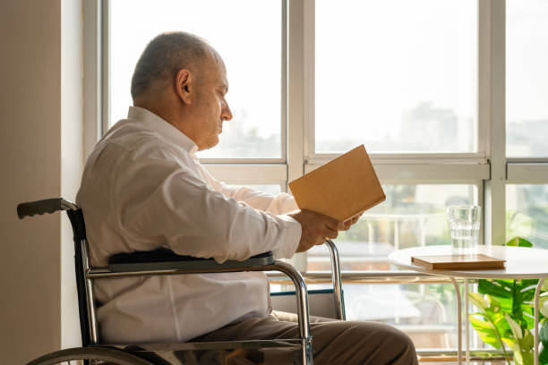 Mature man reading a book in a disabled chair
