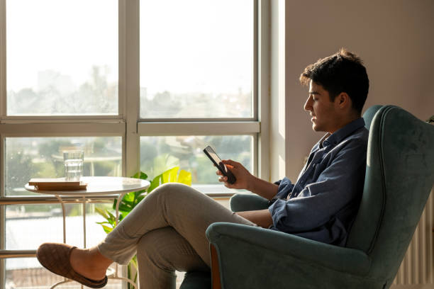 istock young man texting on the phone on the sofa 2052209530
