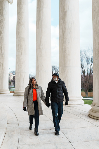 A vibrant senior couple of African American descent hold hands while visiting the Jefferson Memorial during a winter vacation to Washington DC.