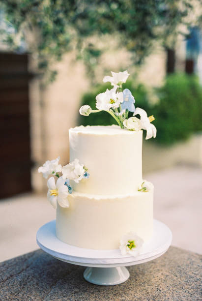 istock Two-tier wedding cake decorated with flowers stands on a tray on the table 2052275178