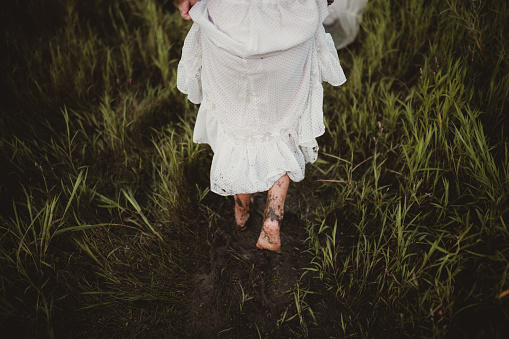 Young girl getting feet full of mud in the summer