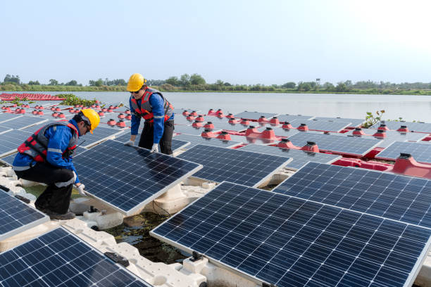istock Male workers repair Floating solar panels on water lake. Engineers construct on site Floating solar panels at sun light. clean energy for future living. Industrial Renewable energy of green power. 2052346260