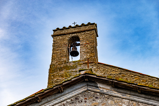 suspended bell, a photograph that could be used for the holidays. the bell is held by a hanger which is connected to a wooden wall.