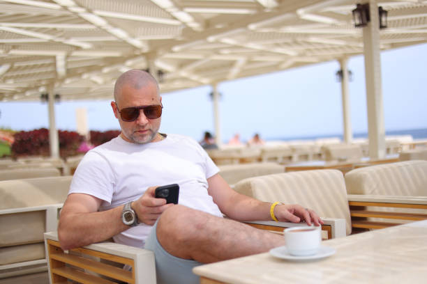 man in sunglasses sits in cafe on vacation in a hotel and is still solving work issues on the phone