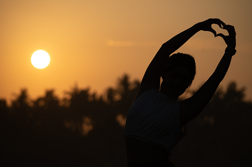 Beautiful Attractive Asian woman practice yoga early in the morning during sunrise beside the pool