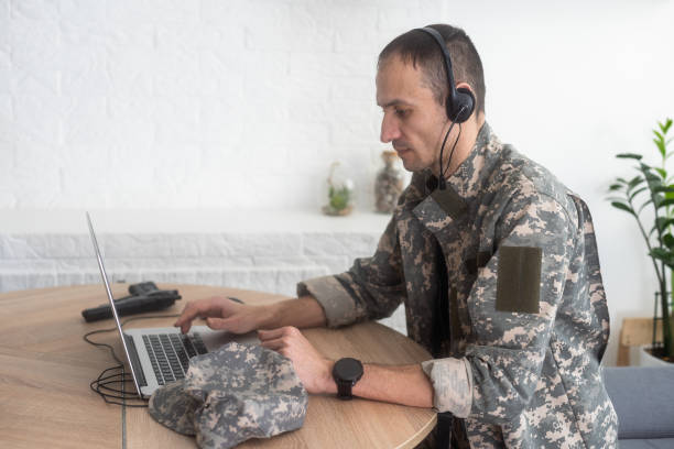 istock smiling soldier in headphones using laptop at kitchen table 2052457319