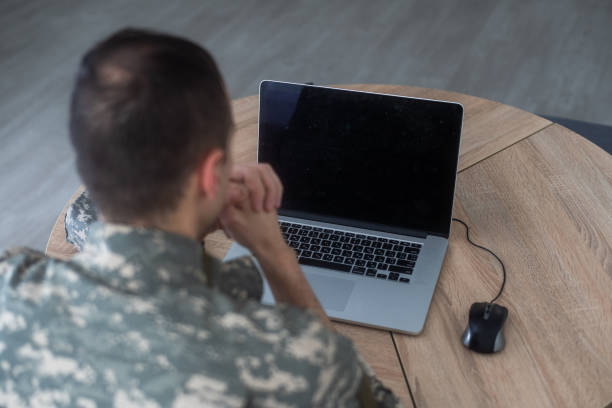 istock Young hispanic man army soldier using laptop sitting on table at home 2052463142