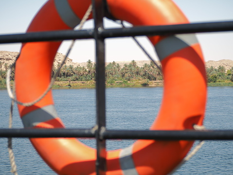 An orange life preserver of a boat is seen on the Nile River, as a safety measure for possible emergencies. The vivid color contrasts with the serene blue of the river.