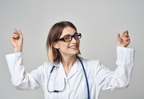 female nurse in a medical gown gesturing with her hands on a light background. High quality photo