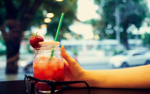 istock glass with a drink in a woman's hand and cafe 2052531920