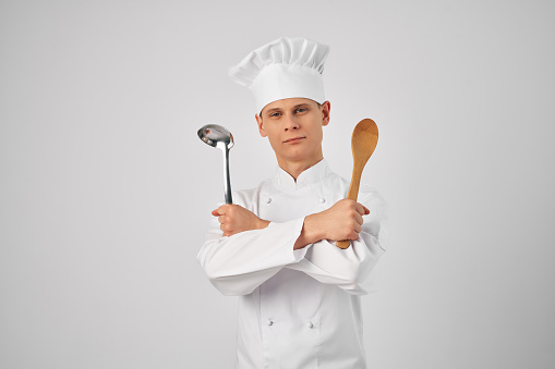 Cheerful male chef with kitchen utensils Professional light background. High quality photo