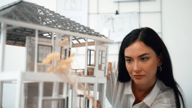 istock Skilled architect turns house model around to inspect construction. Immaculate. 2052579615