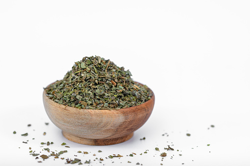 Dried oregano spice in a wooden bowl on a light background