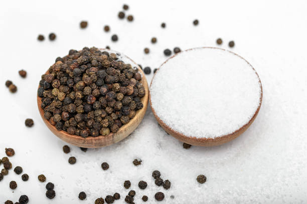 istock Two wooden bowls with table salt and black pepper isolated on light background 2052582327