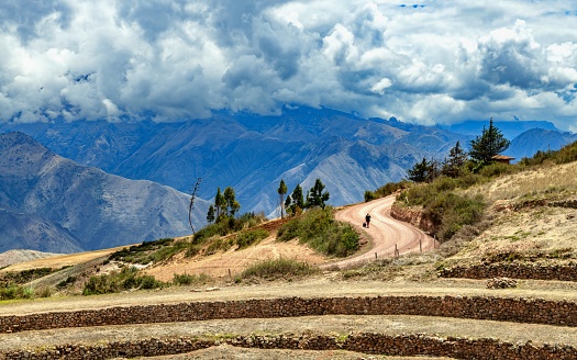 Maras, Peru, November 13, 2021: A woman goes down the road in the Incan agriculture locality of Moray, archaeological site in Peru 50 kilometres northwest of Cusco on a high plateau at about 3,500 metres and just west of the village of Maras.