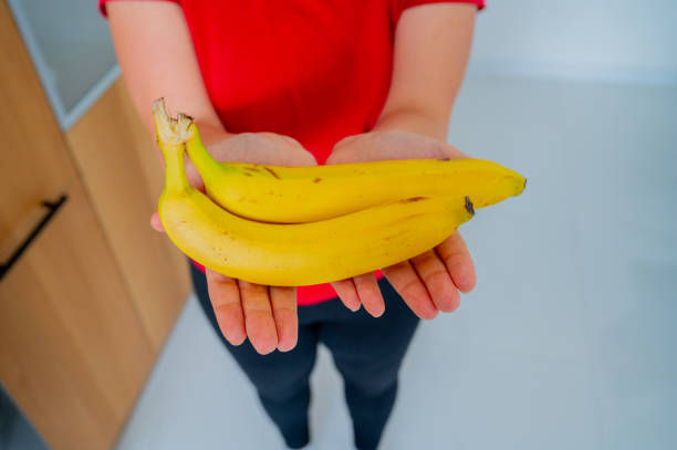 istock Woman hands holding bananas, natural daylight 2052595976