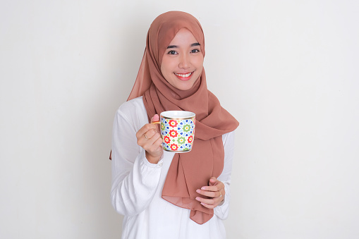 Moslem Asian woman smiling happy while holding a drinking glass
